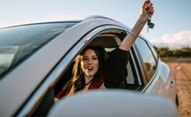Imagem de uma mulher dentro do carro com a chave do carro na mão